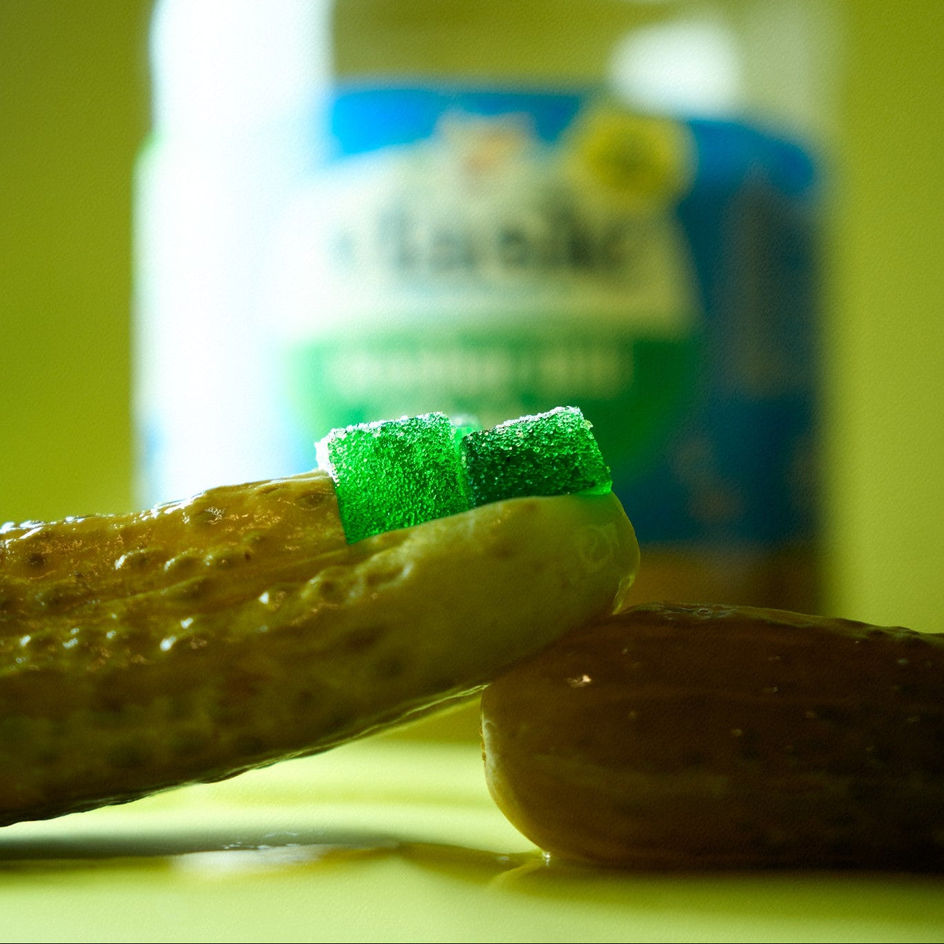 Jar of pickles with a pickle gummy on a yellow-green background
